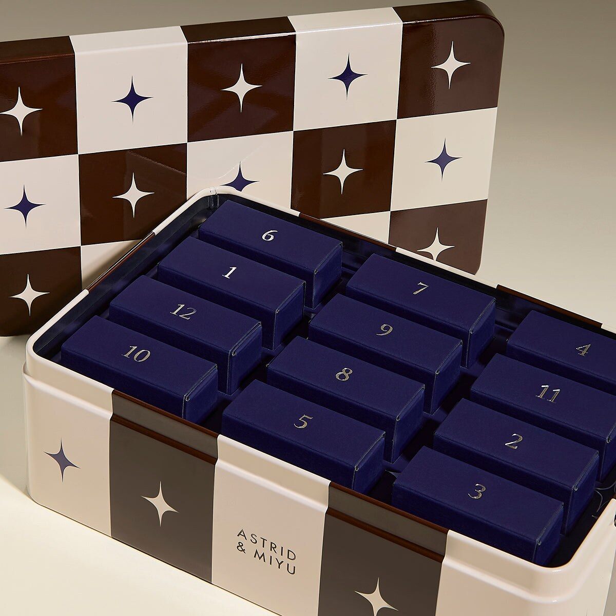 The Astrid & Miyu 12 Day advent calendar in a brown and cream checkerboard tin with navy star doors