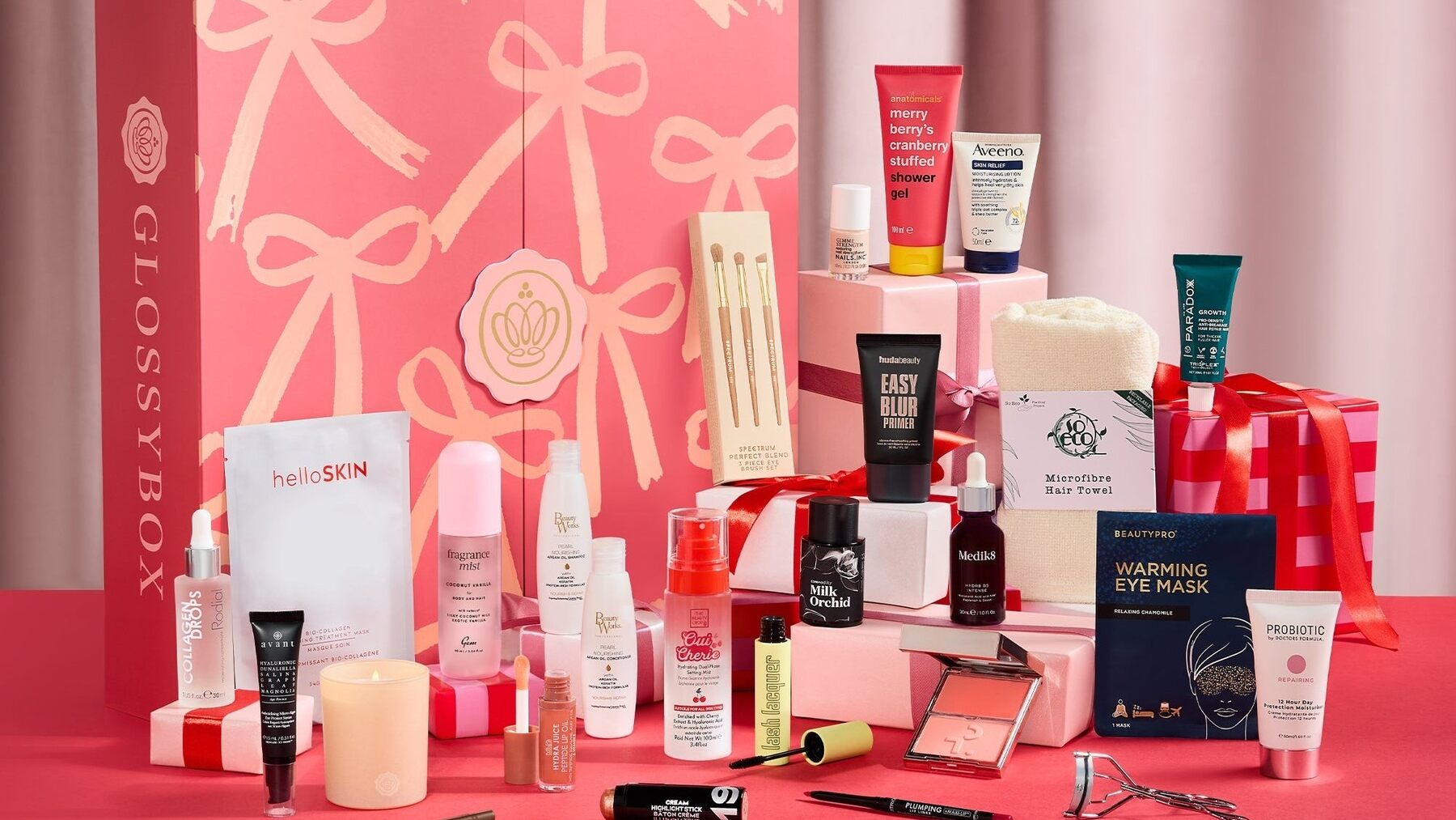 The GLOSSYBOX advent calendar 2026 in pink with its beauty products laid out in front