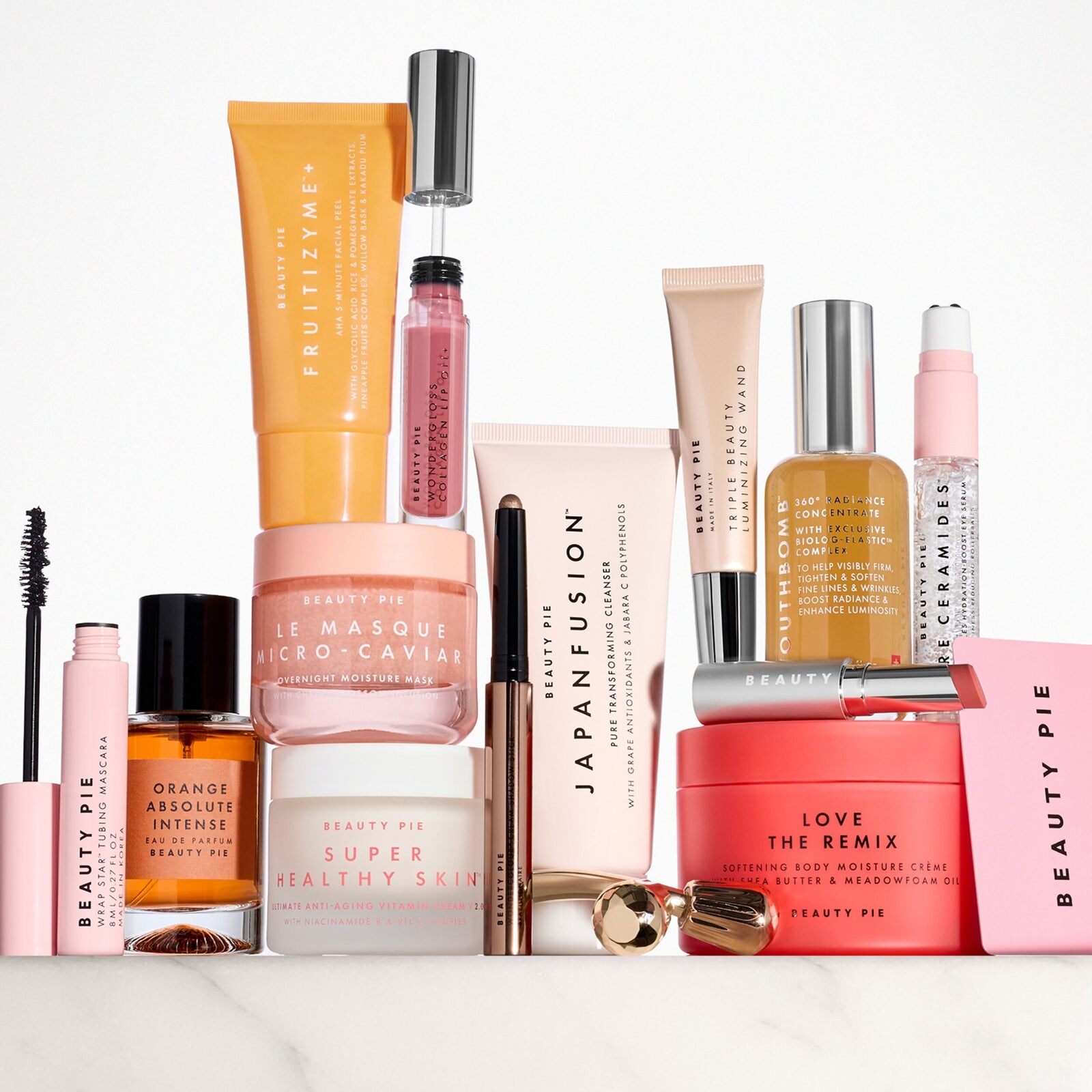 The 14 Beauty Pie products standing in a row with their boxes, from serums and creams to perfume and lip products