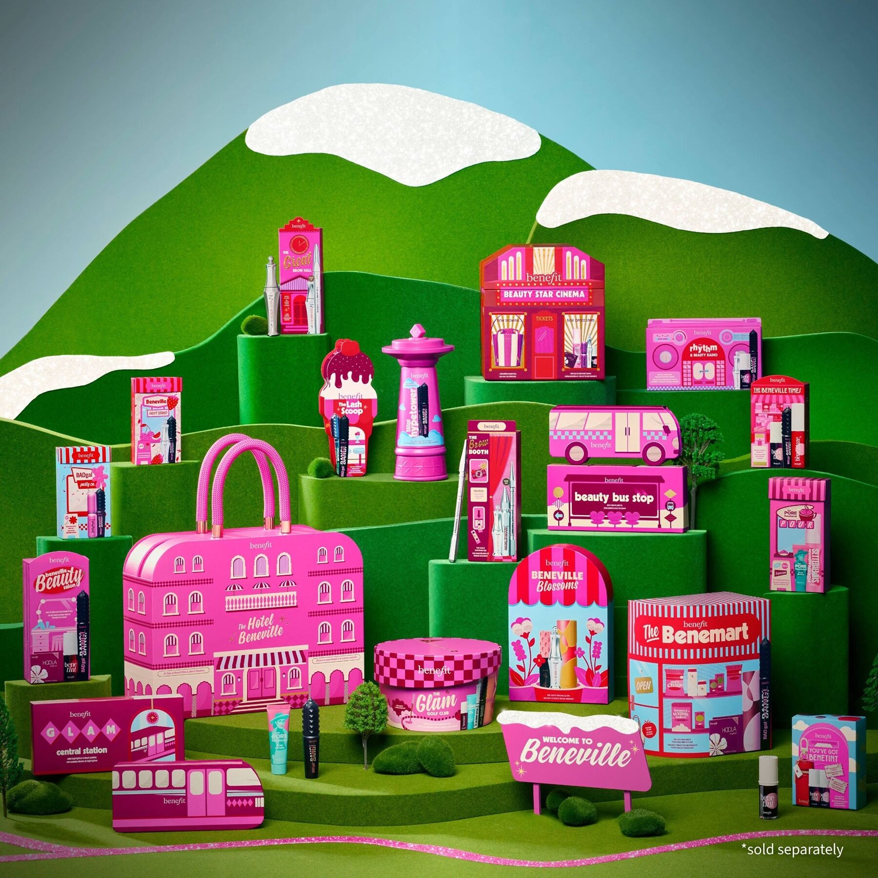 The Benefit Hotel Beneville advent calendar 2026 in a green hillside scene surrounded by Benefit make-up products