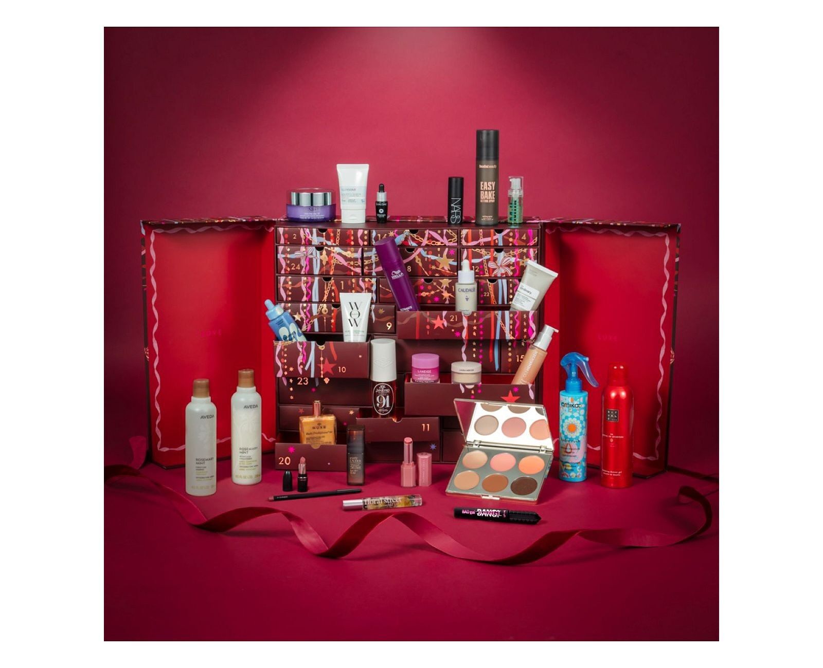 The Boots 24 Days of Luxe beauty advent calendar 2026 open on a red background, its drawers filled with beauty products