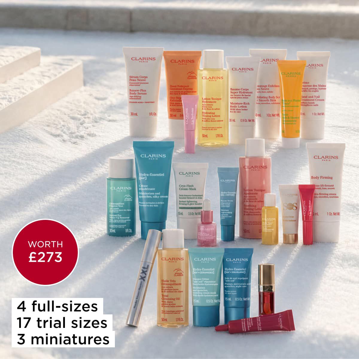 The Clarins advent calendar 2026 products laid out in the snow, with a badge showing four full sizes, 17 trial sizes and three miniatures