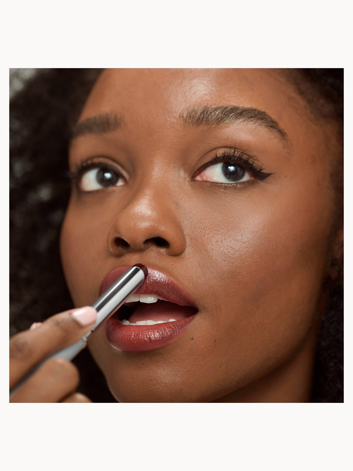 A woman applying Clinique Almost Lipstick in Black Honey
