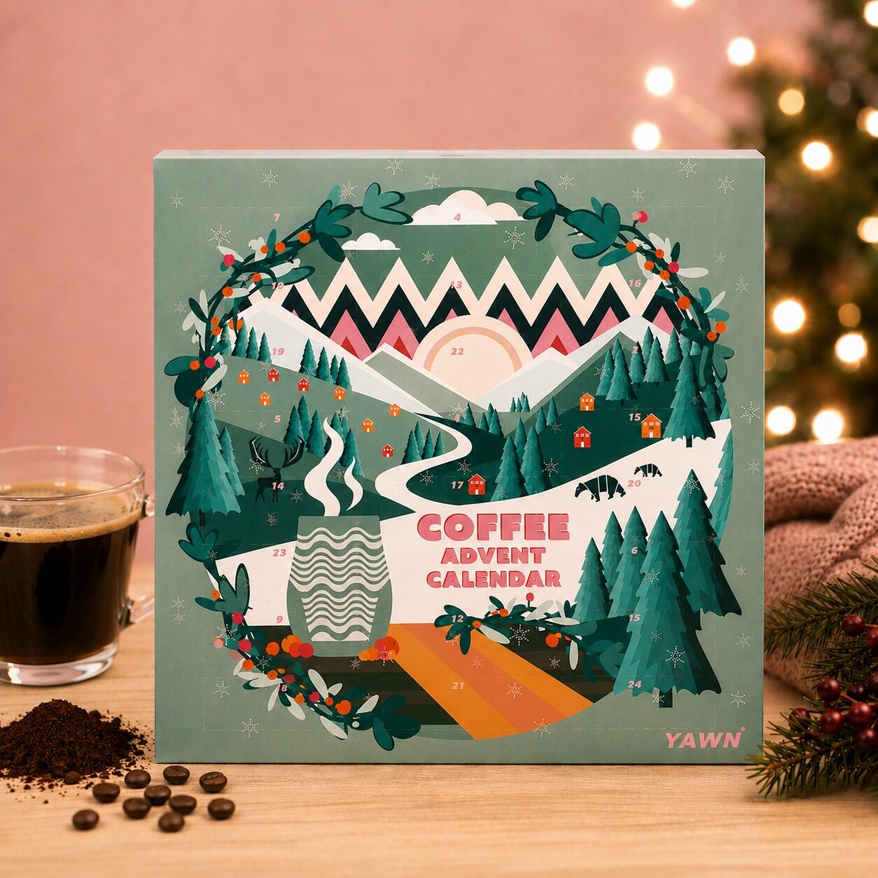 The green Yawn Coffee Advent Calendar with an illustrated mountain landscape, next to a cup of black coffee