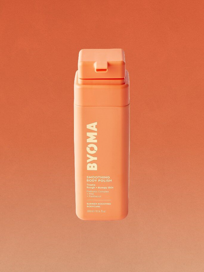 A bottle of BYOMA Smoothing Body Polish on an orange background