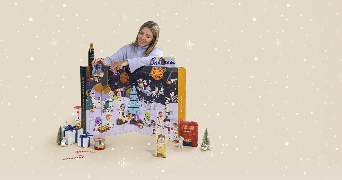 A woman opening a door of the space-themed Degustabox Cosmic Christmas advent calendar 2026 surrounded by food products
