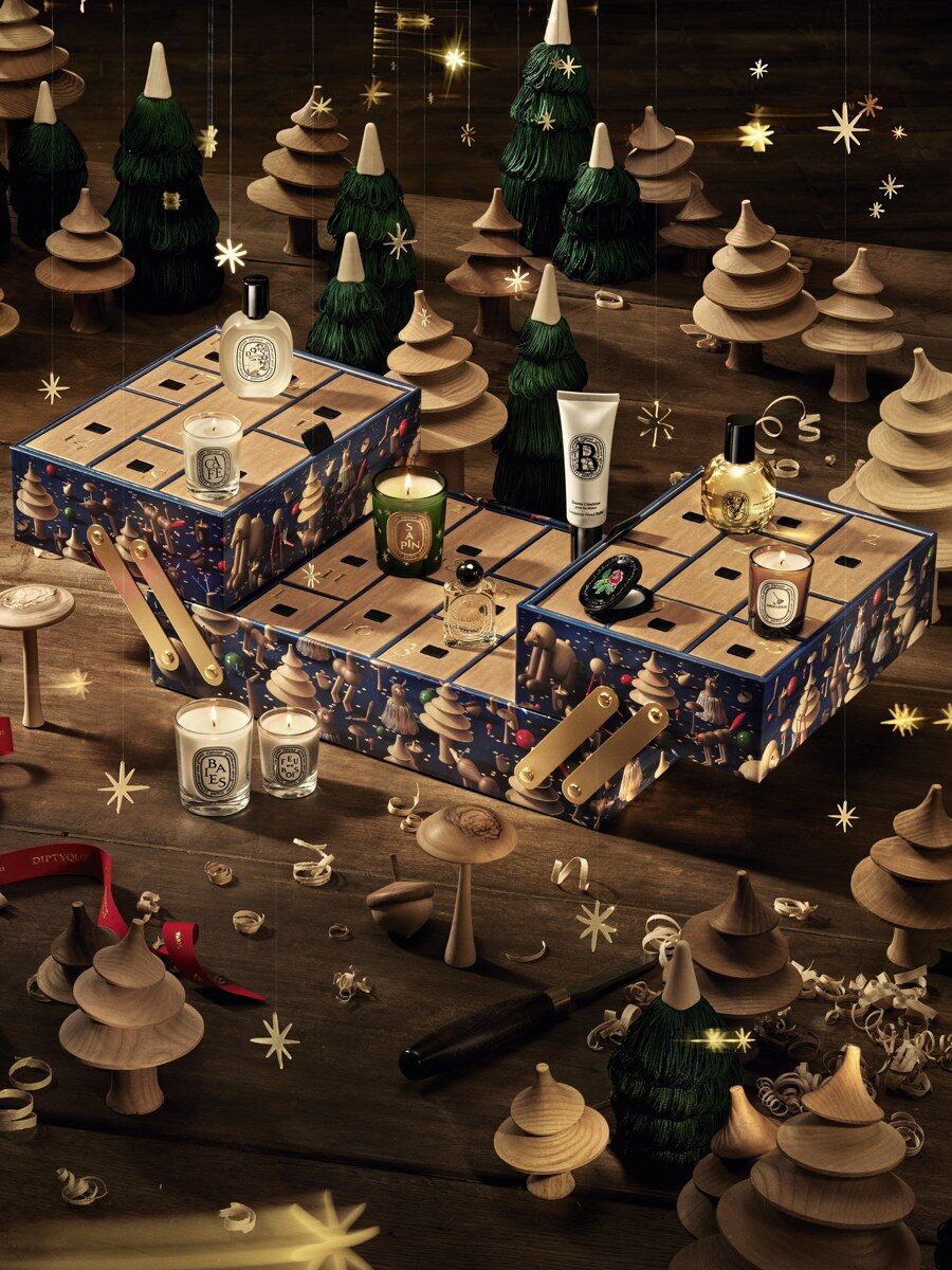 The open Diptyque advent calendar 2026 with candles and perfumes in its drawers among gold Christmas decorations