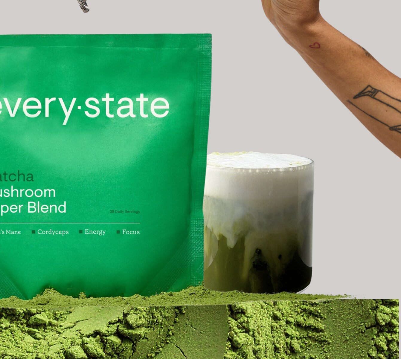 A green pouch of everystate Matcha + Mushroom Super Blend next to a glass of iced matcha latte