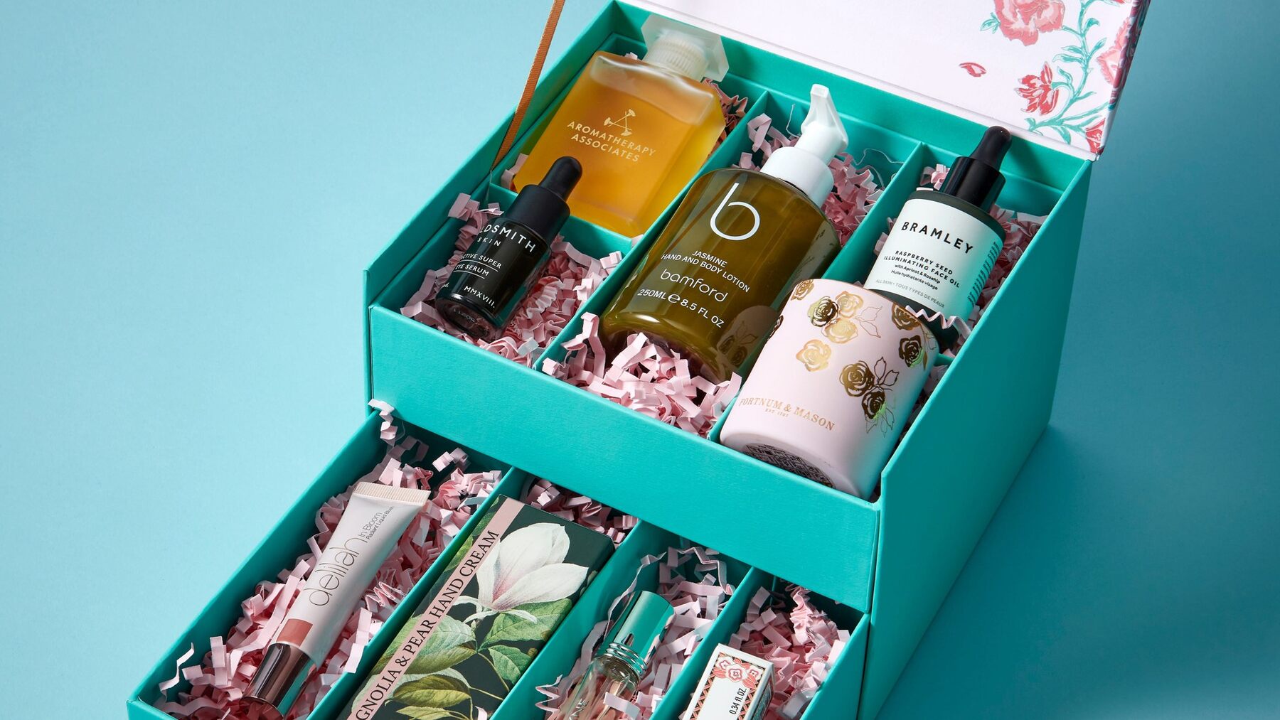 The open turquoise Fortnum's Beauty Box with Aromatherapy Associates, Bamford and Bramley products in its compartments