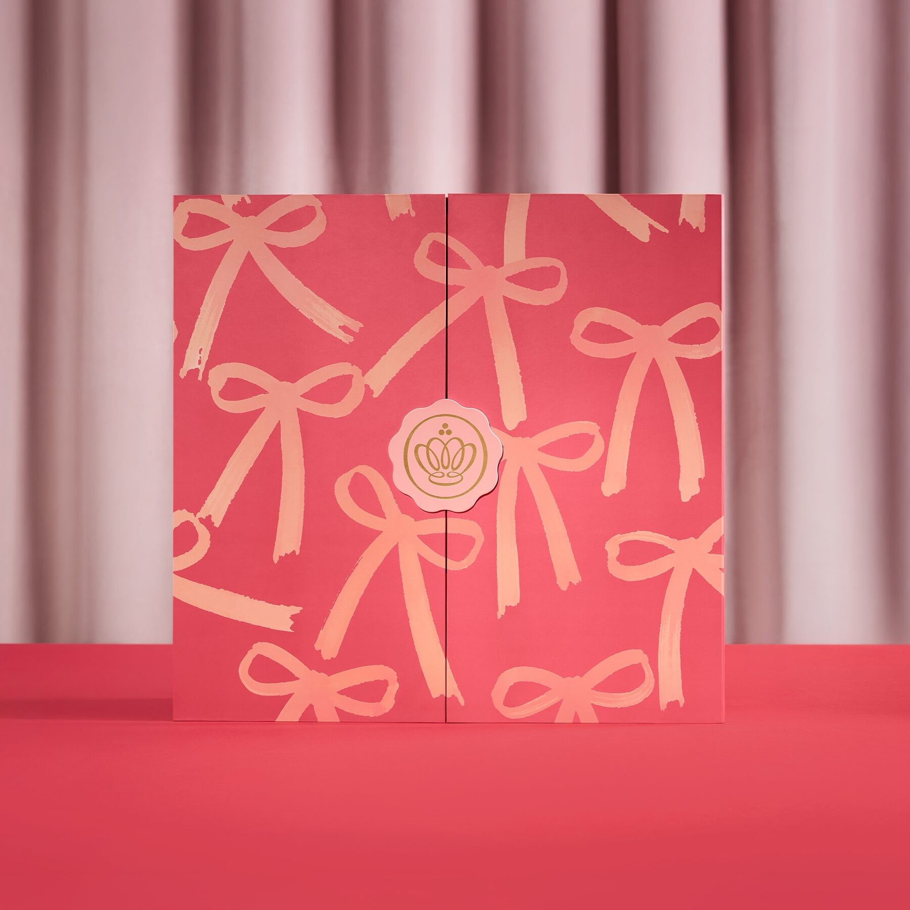 The closed GLOSSYBOX advent calendar 2026 in red and pink with a ribbon print