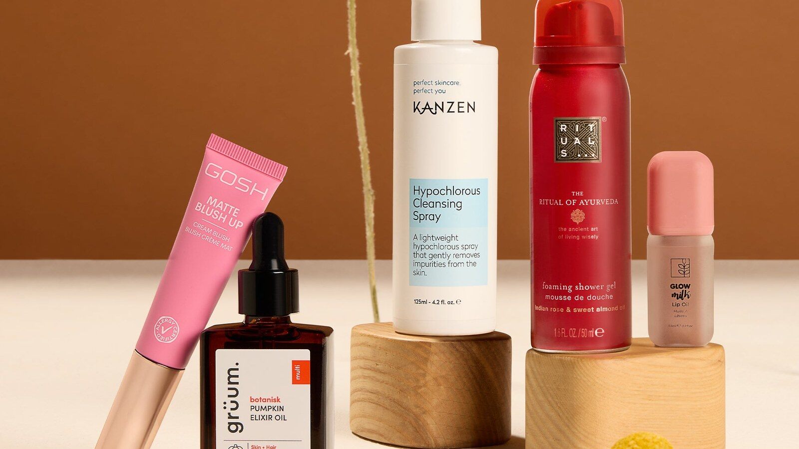 GLOSSYBOX October products including a Kanzen spray, Rituals shower gel and GOSH blush on wooden stands
