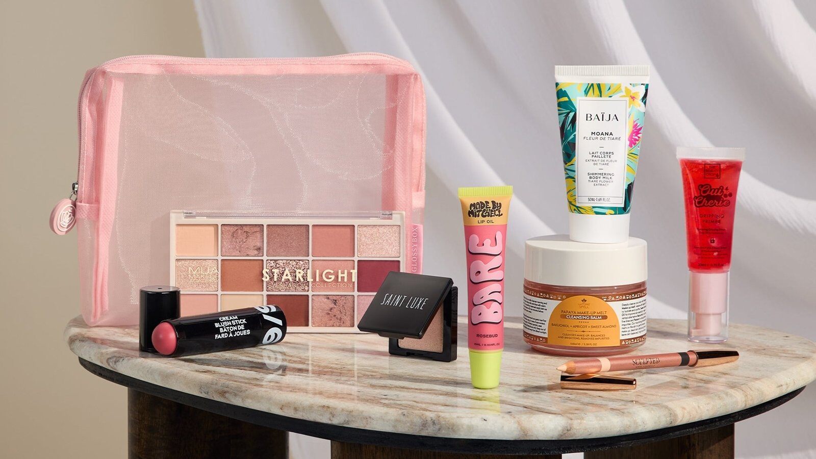 The GLOSSYBOX Spotlight Edit products and pink pouch on a marble side table