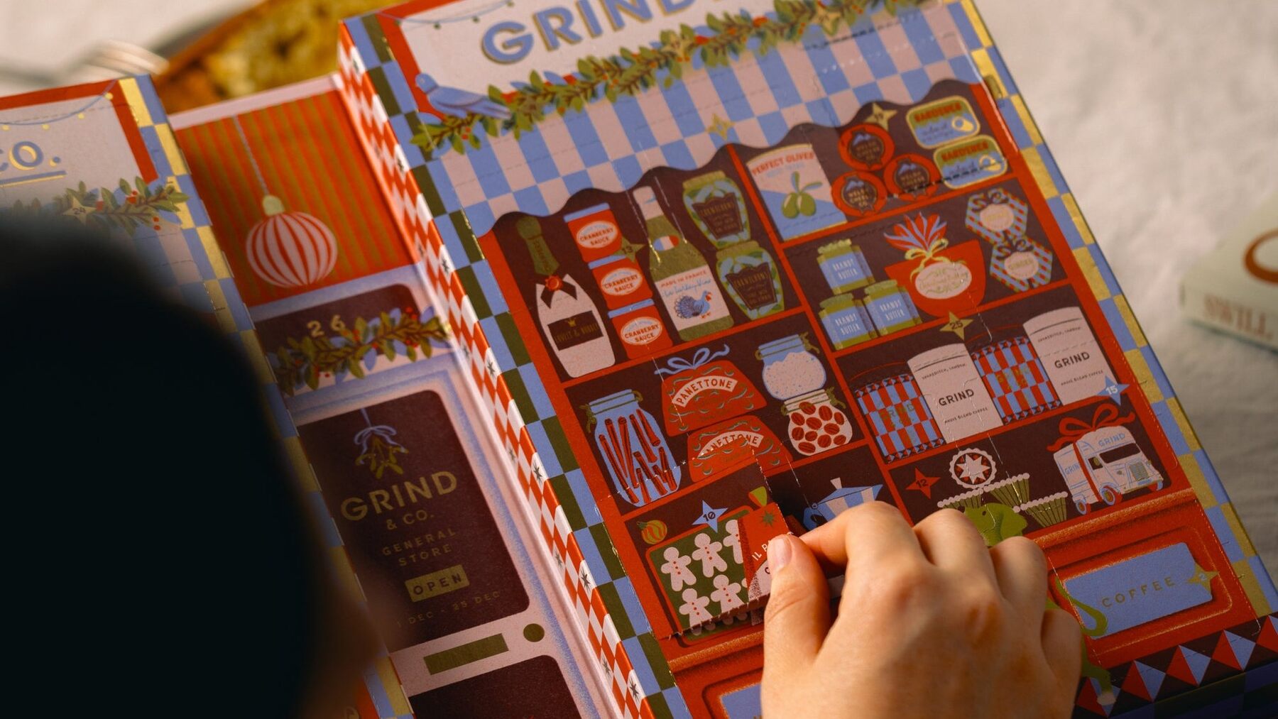 Hands opening the Grind Coffee Pod Advent Calendar 2026 on a table
