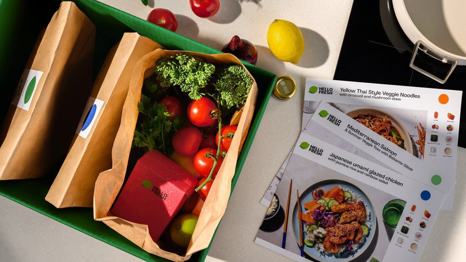 A HelloFresh box with fresh vegetables, ingredient bags and recipe cards
