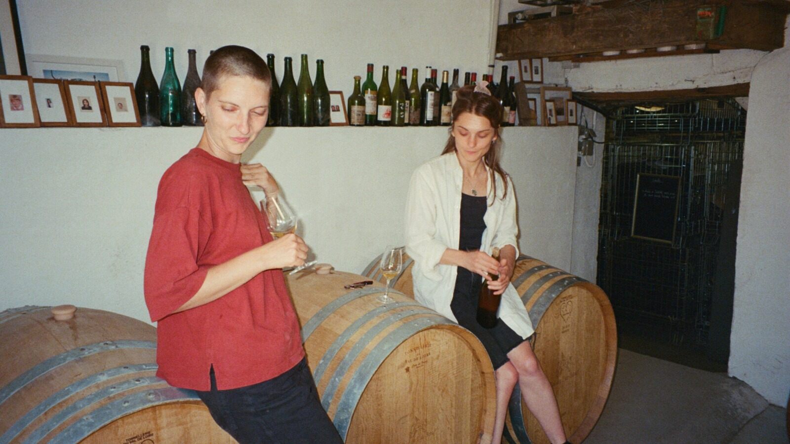 A man and a woman tasting wine on oak barrels in a winemaker's cellar
