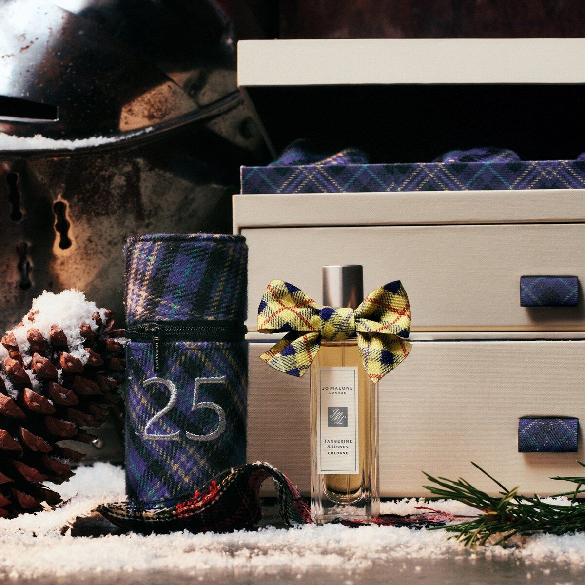 A tartan tube numbered 25 opening to reveal the Jo Malone Tangerine and Honey cologne