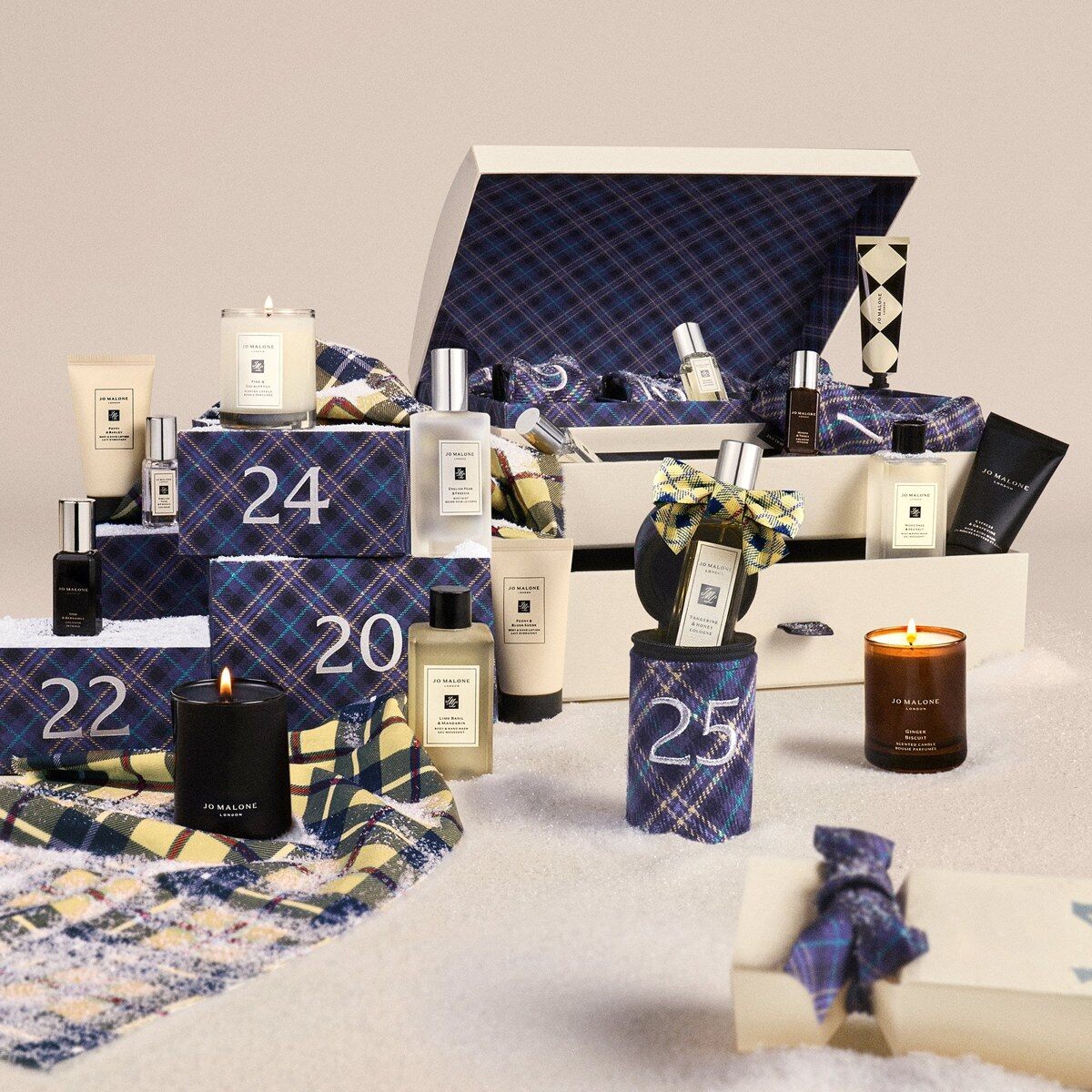 The open Jo Malone London Christmas Kist advent calendar 2026 with tartan crackers, colognes and candles in the snow