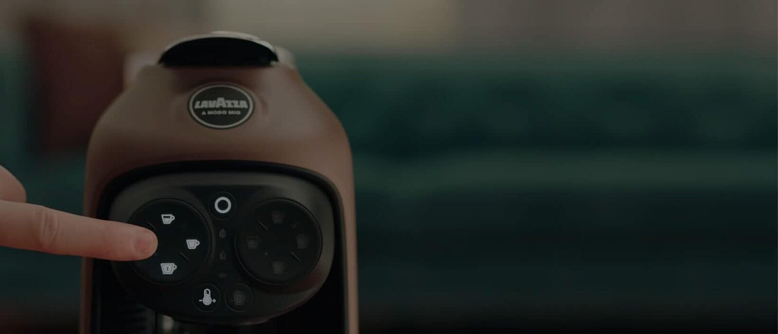 Finger pressing the button on a Lavazza A Modo Mio capsule machine