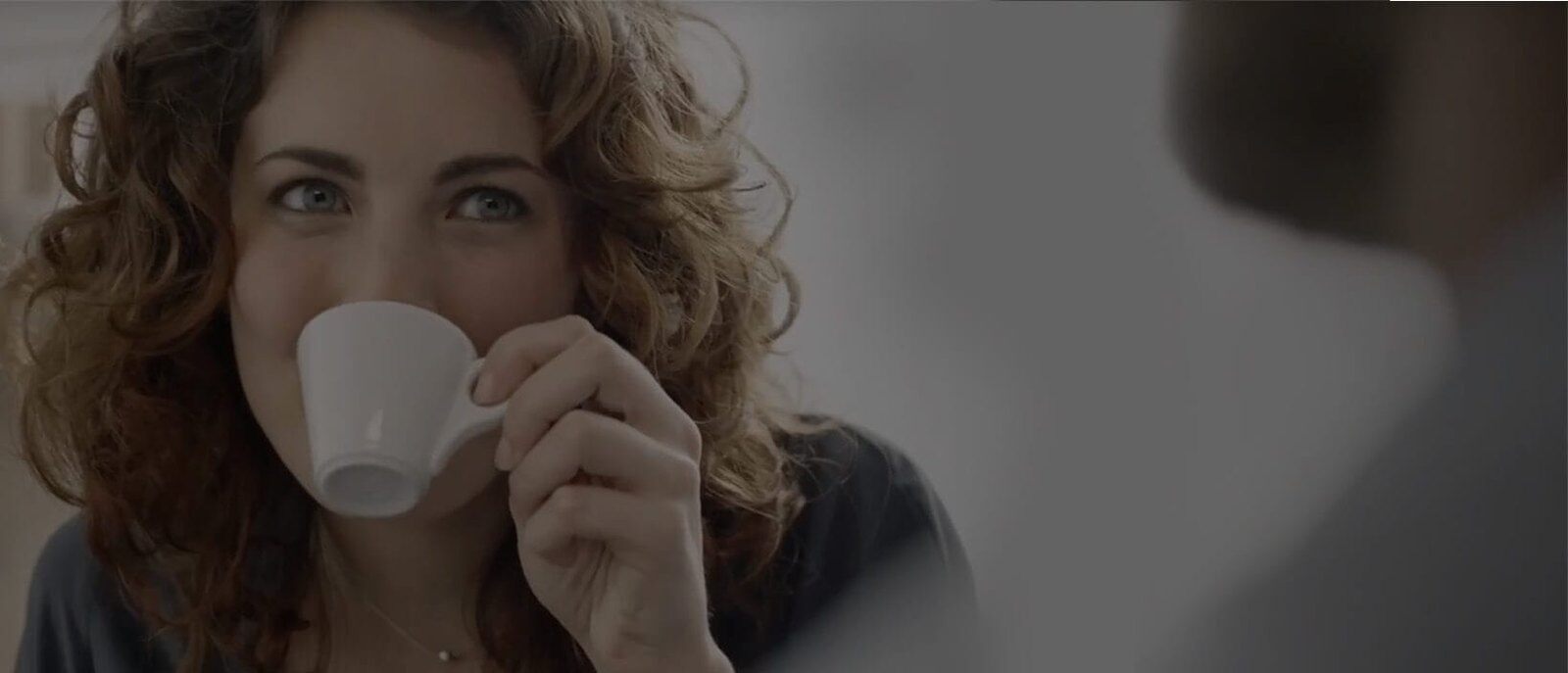 Woman drinking an espresso from a white Lavazza cup