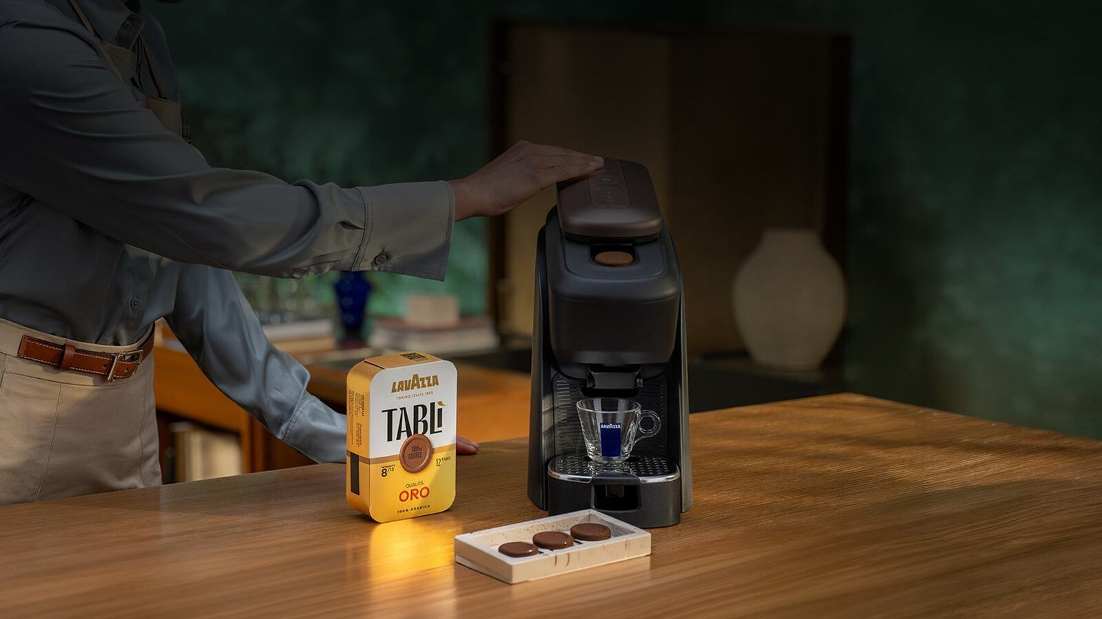 Man making coffee with a Lavazza Tablì machine next to a pack of tabs