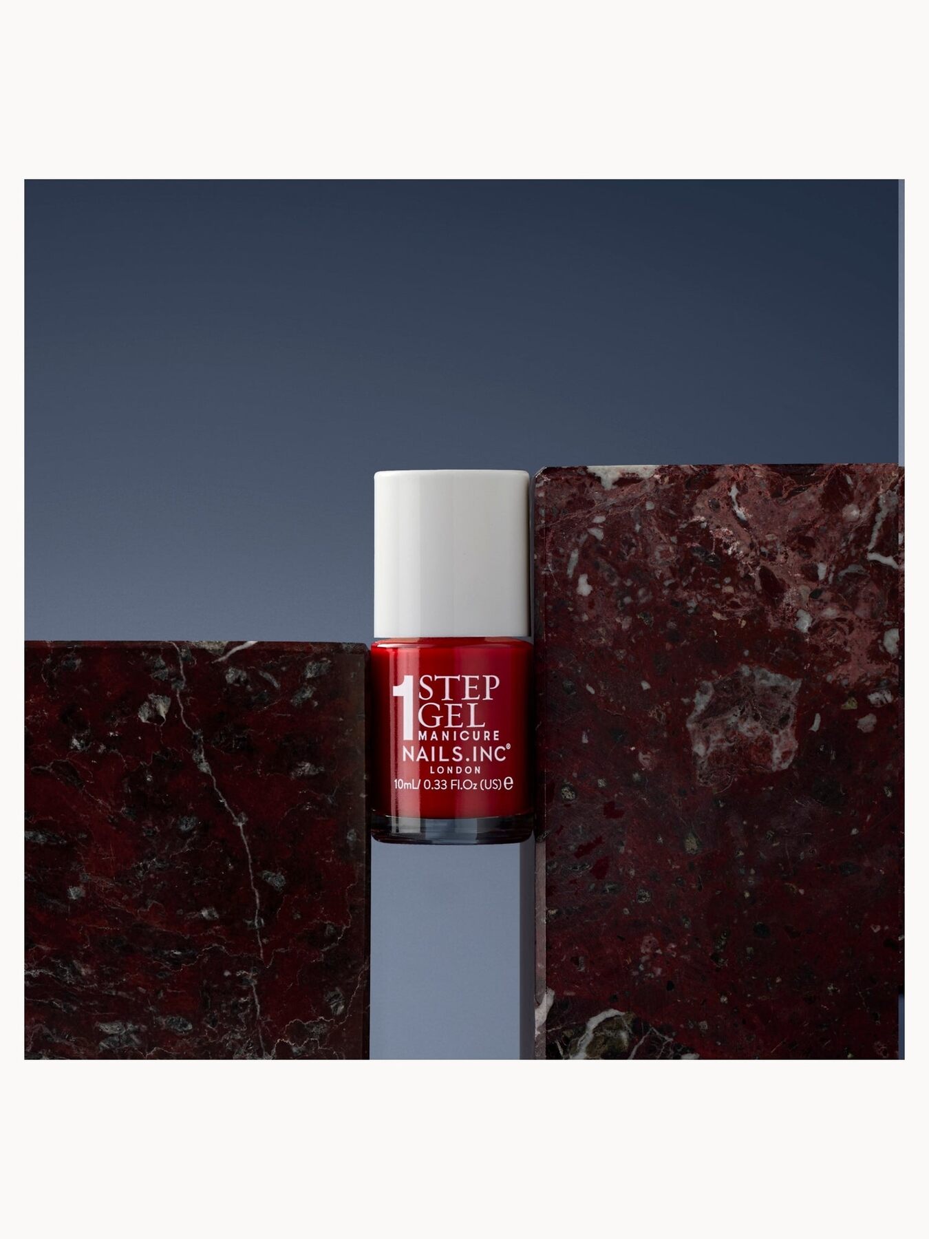 A bottle of red Nails Inc nail polish in Kendall on a dark marble block