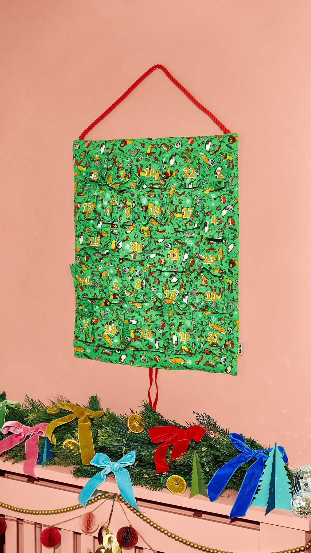 The green Lush Fabric Advent Calendar 2026 with 25 printed pockets hanging above a fireplace