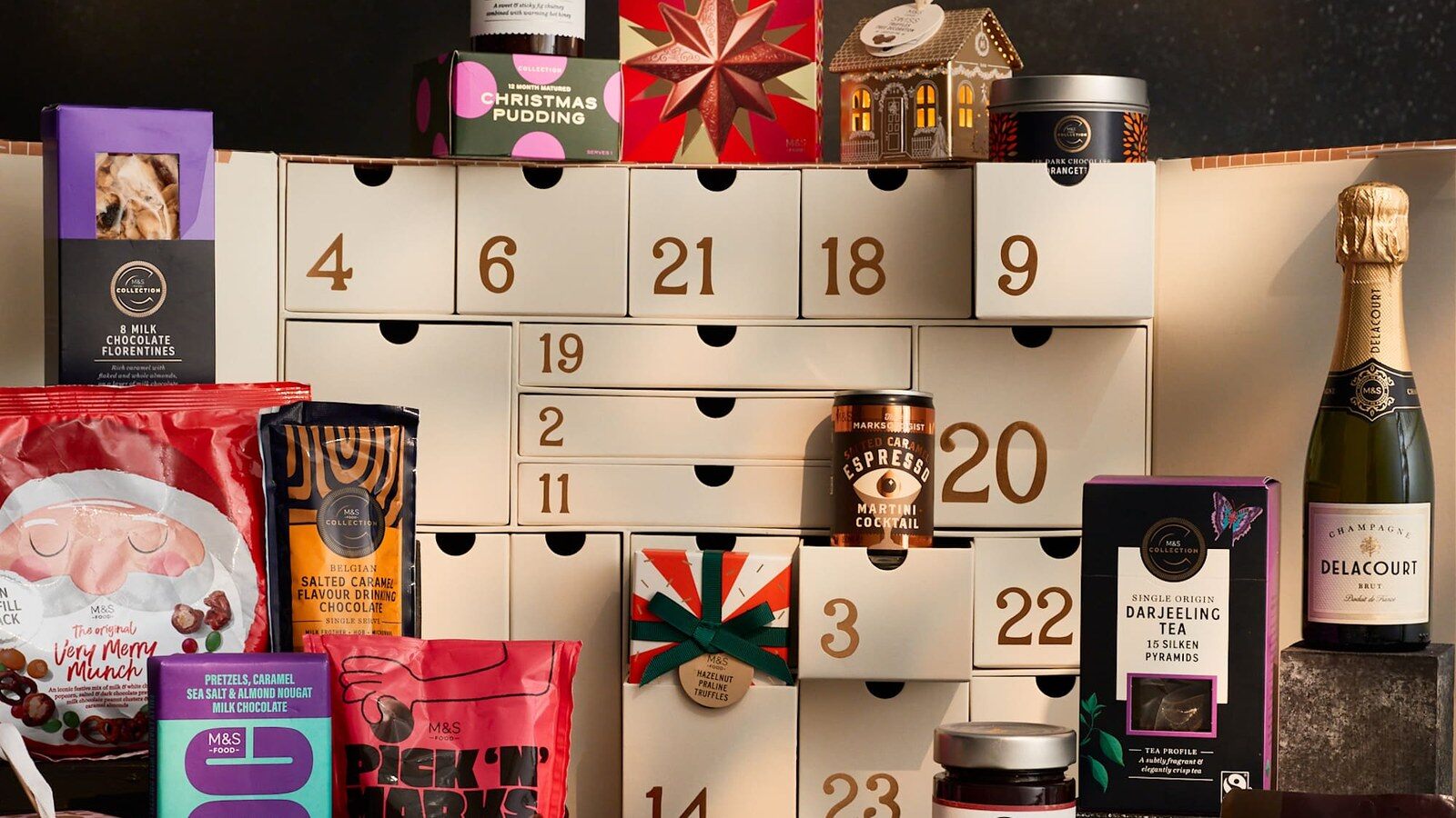 The M&S Foodhall advent calendar drawers surrounded by chocolates, tea, chutney and a mini champagne bottle