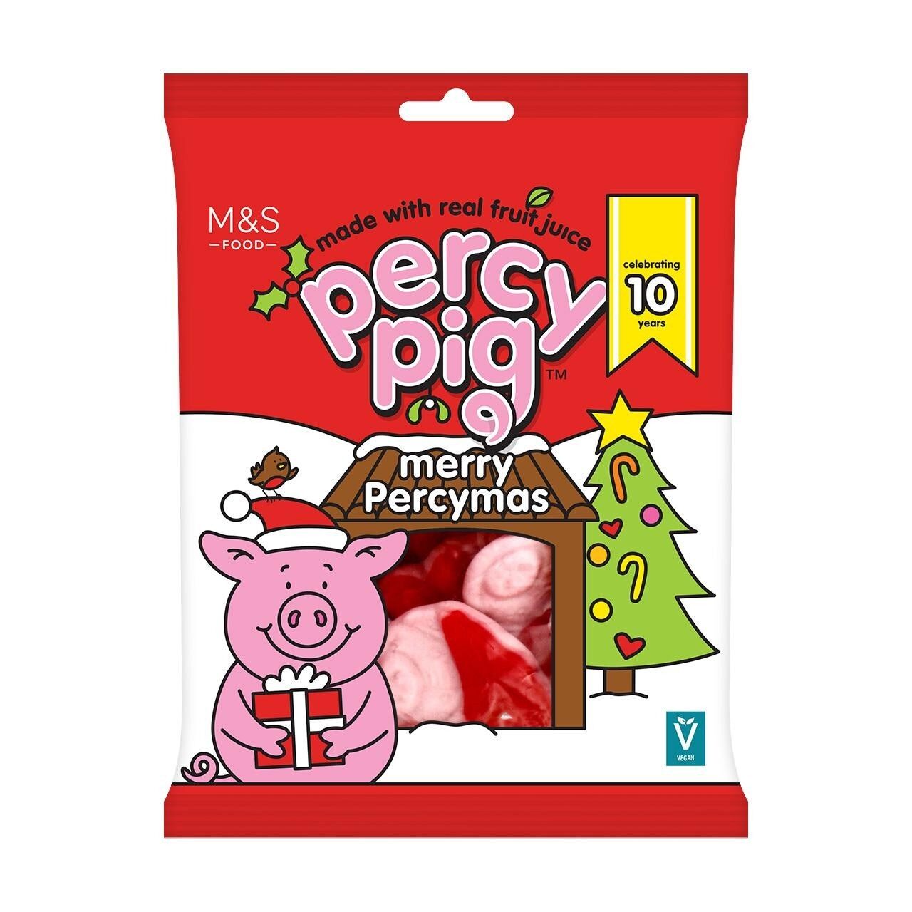 A bag of M&S Percy Pig Merry Percymas sweets with Percy in a Christmas jumper next to a decorated tree