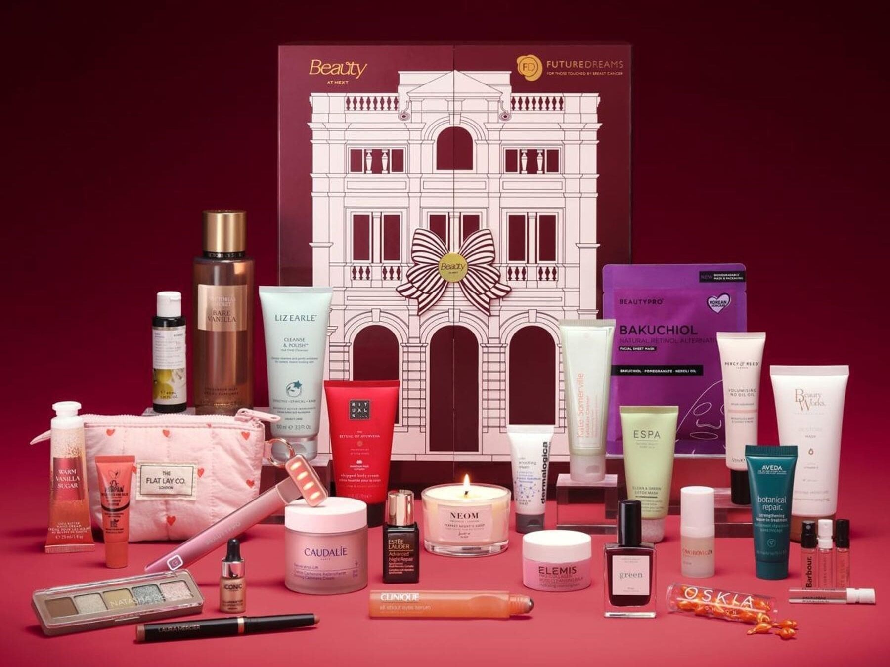 The Next beauty advent calendar 2026, a pink and burgundy townhouse box with a striped bow, surrounded by its products on a red background