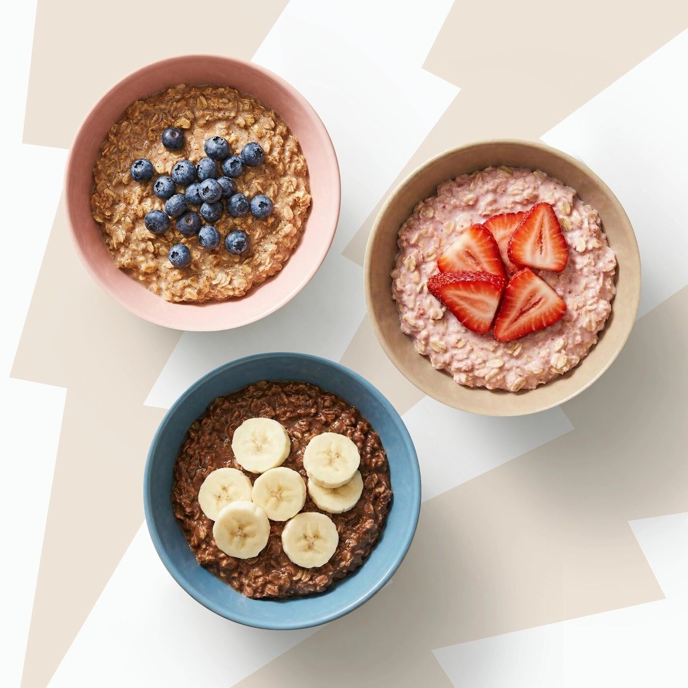 Three bowls of Oat Cult overnight oats topped with blueberries, strawberries and banana