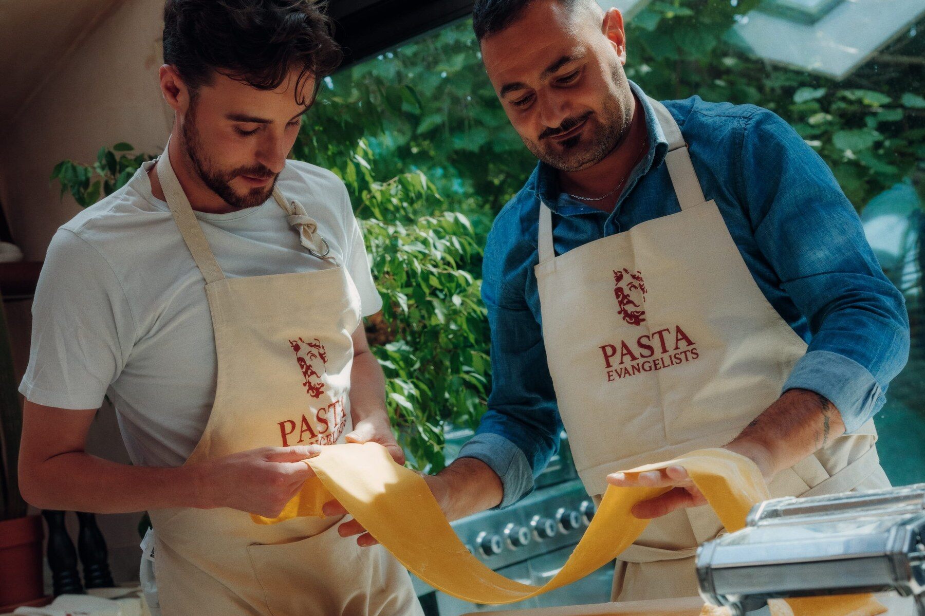 Two Pasta Evangelists chefs rolling a sheet of fresh egg pasta