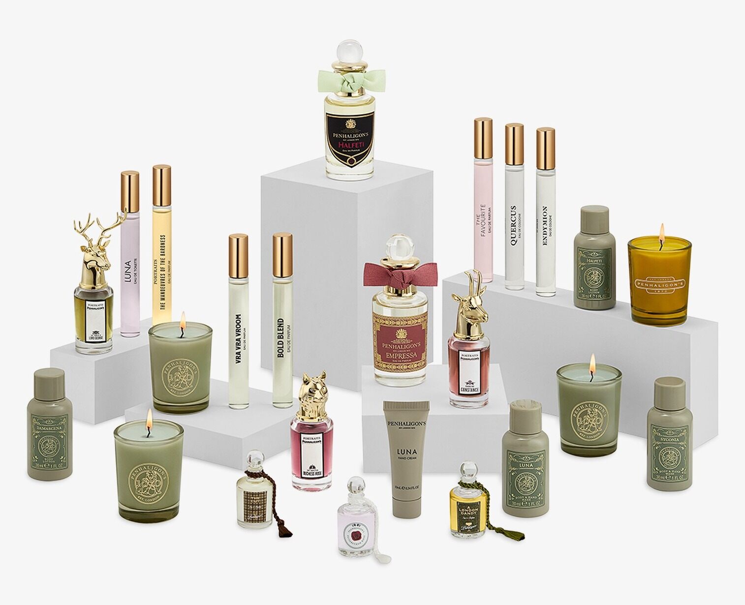 The Penhaligon's advent calendar 2026 products arranged on white plinths, with perfume bottles, animal-headed Portraits flacons, travel sprays, candles and body care bottles