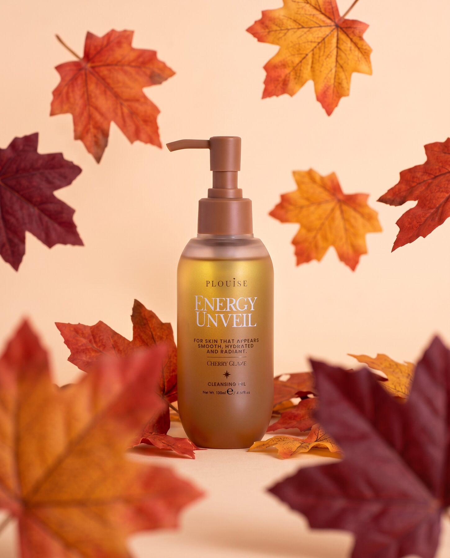 A bottle of P.Louise Energy Unveil Cleansing Oil among falling autumn leaves