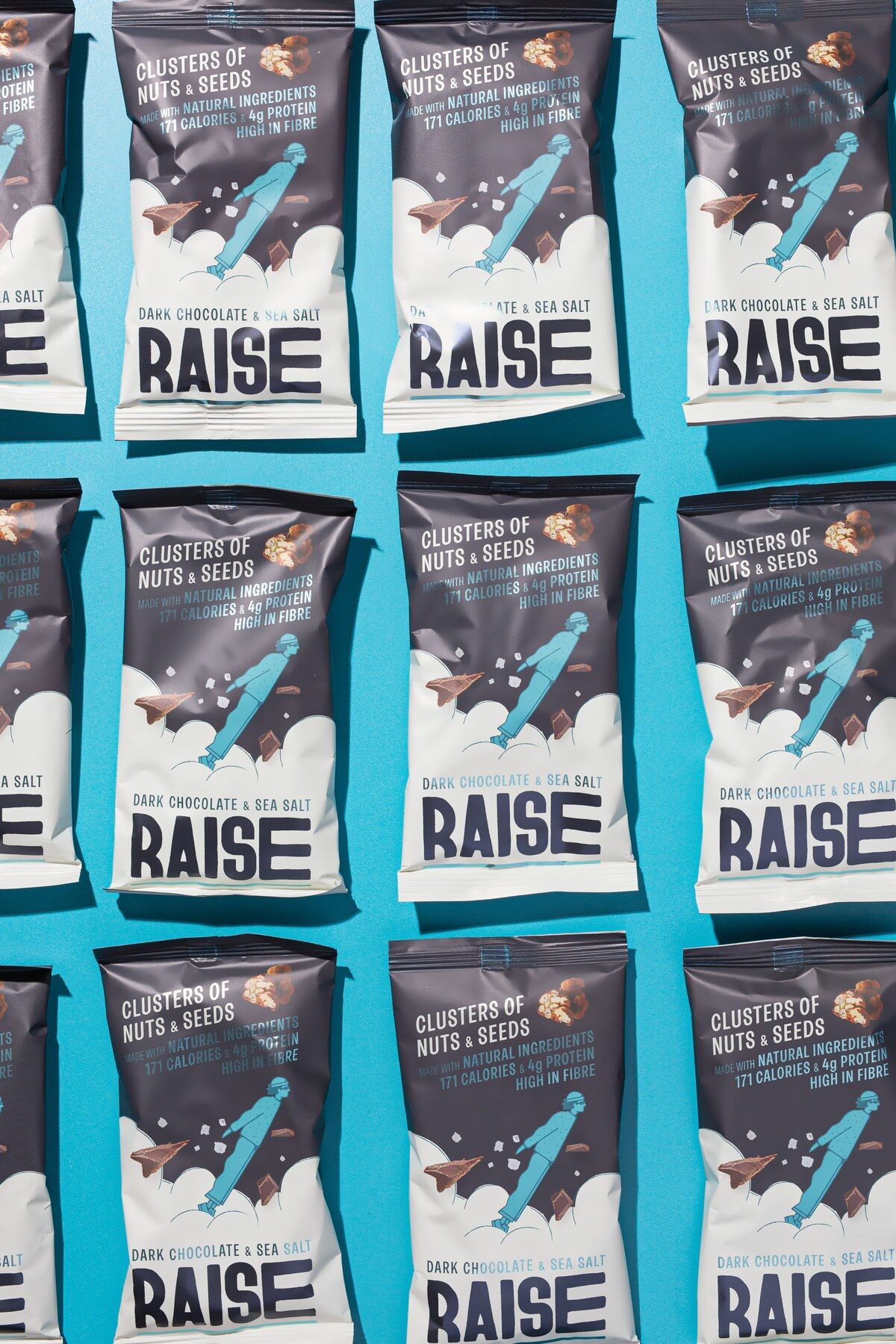 Rows of RAISE Dark Chocolate and Sea Salt bags laid out on a blue background