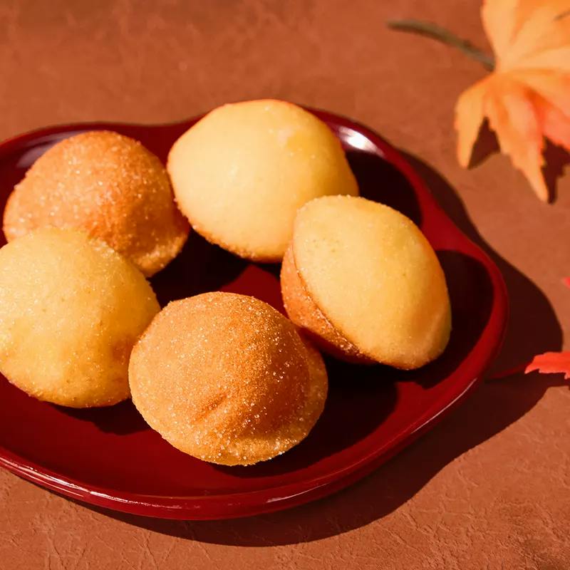 Small round golden castella cakes on a red lacquered dish