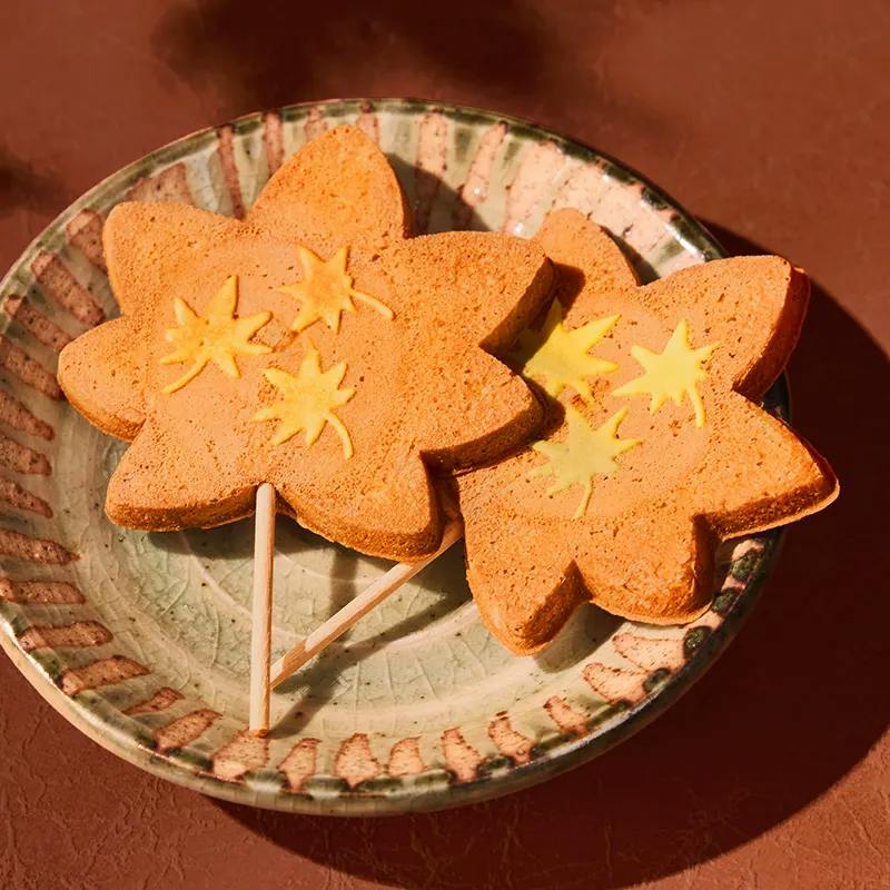 Several maple leaf-shaped crackers with star decorations on a ceramic plate