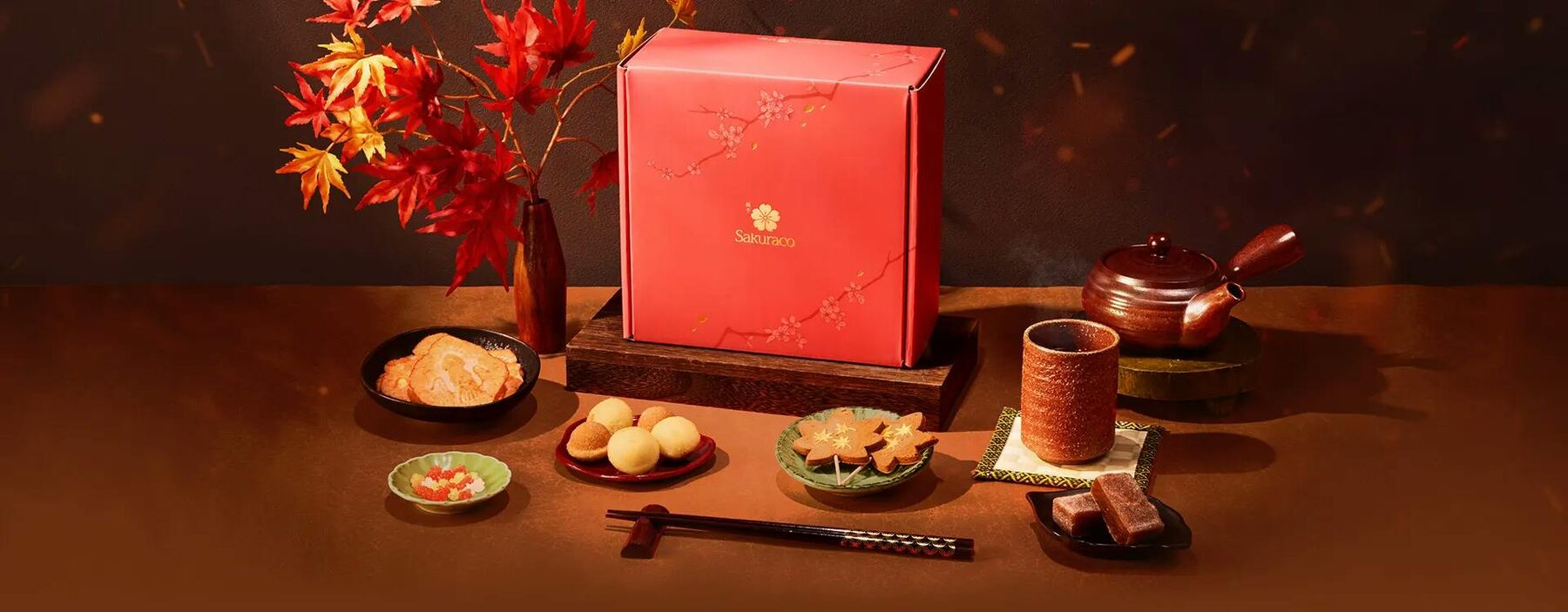 The Sakuraco November 2026 box spread out on a wooden table with tea, autumn snacks, chopsticks and maple leaves