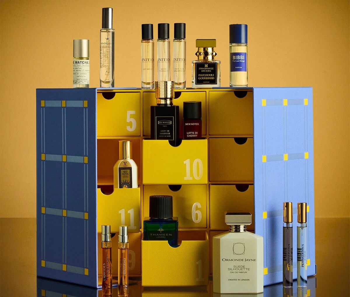 The Selfridges 2026 fragrance advent calendar, a blue and yellow box with drawers, surrounded by its 16 perfume bottles