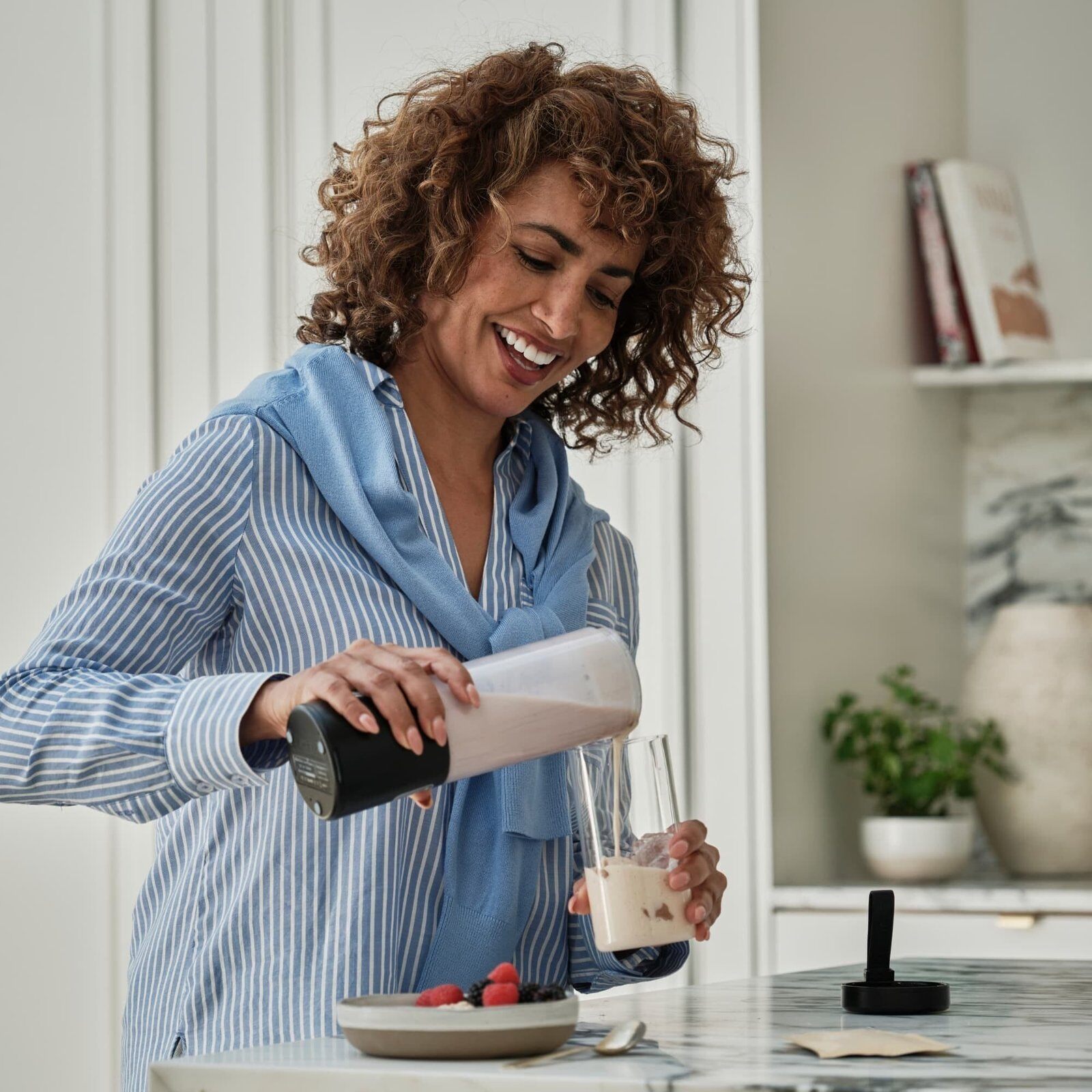 A woman mixing a Serenova Balance & Boost drink in her kitchen