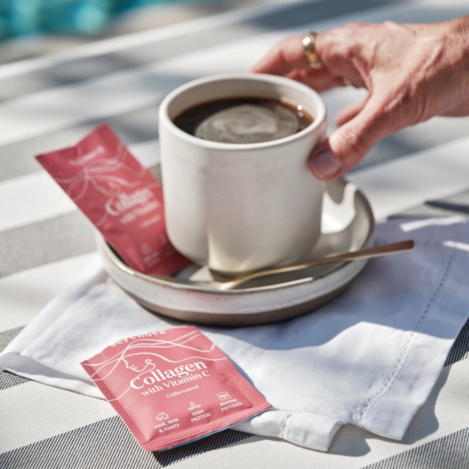 A Serenova Collagen sachet next to a cup of coffee on a saucer