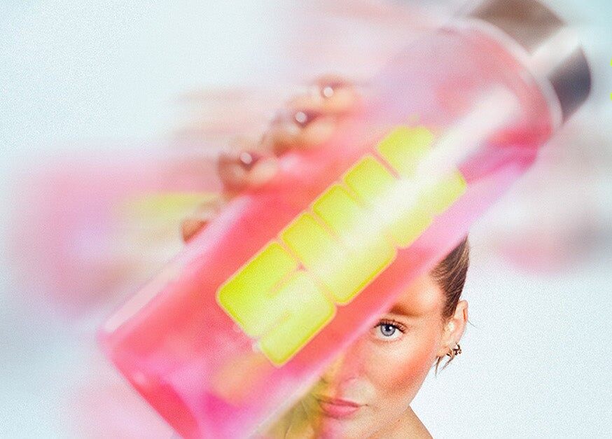 A pink SULT water bottle held up close to the camera