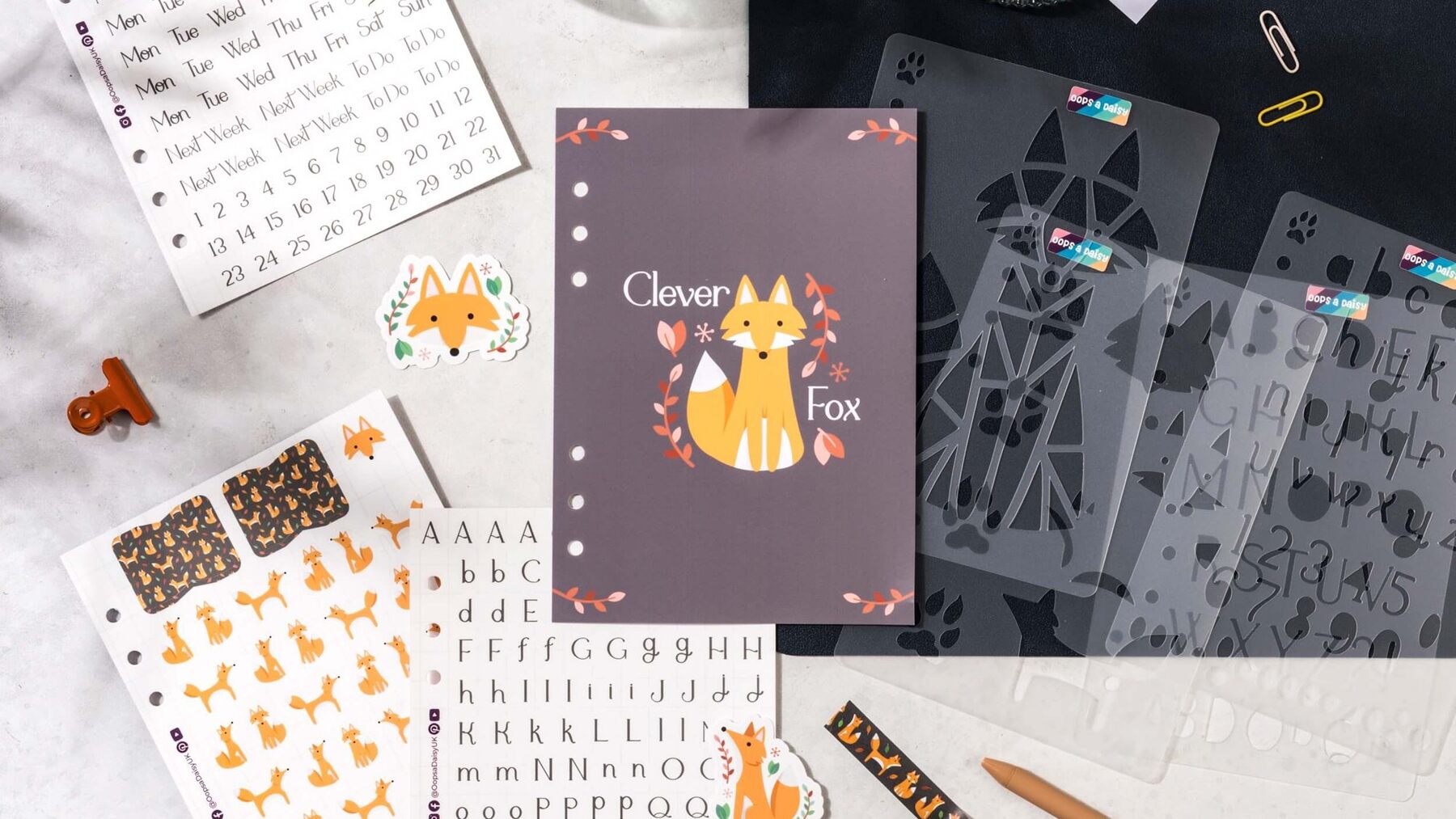 A Themebox journaling flat lay with Clever Fox stickers, stencils, washi tape and a dashboard card on a desk