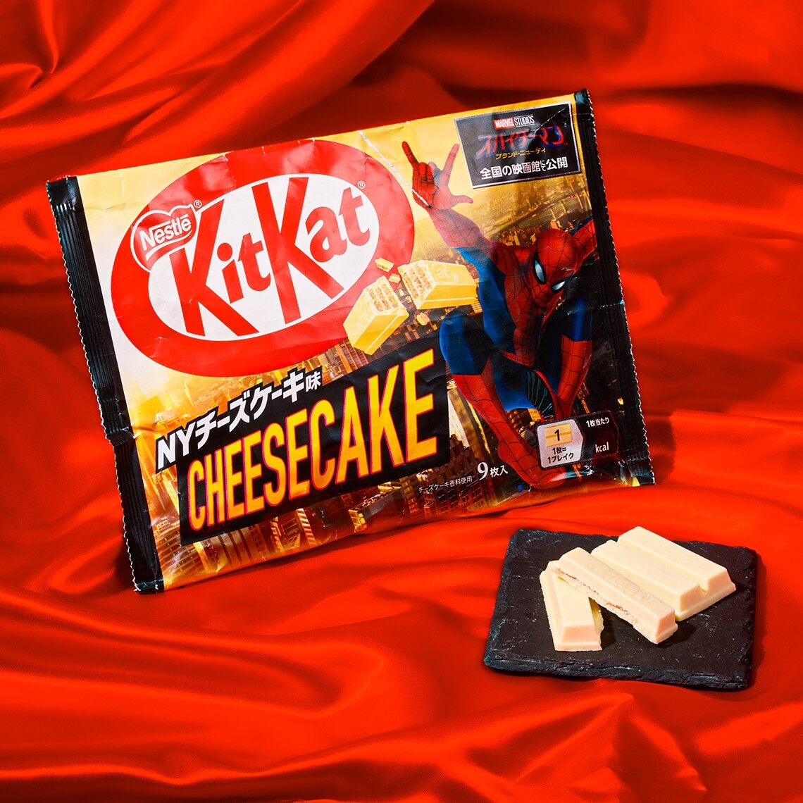 A pack of Japanese NY Cheesecake KitKats with Spider-Man artwork, next to unwrapped KitKat fingers