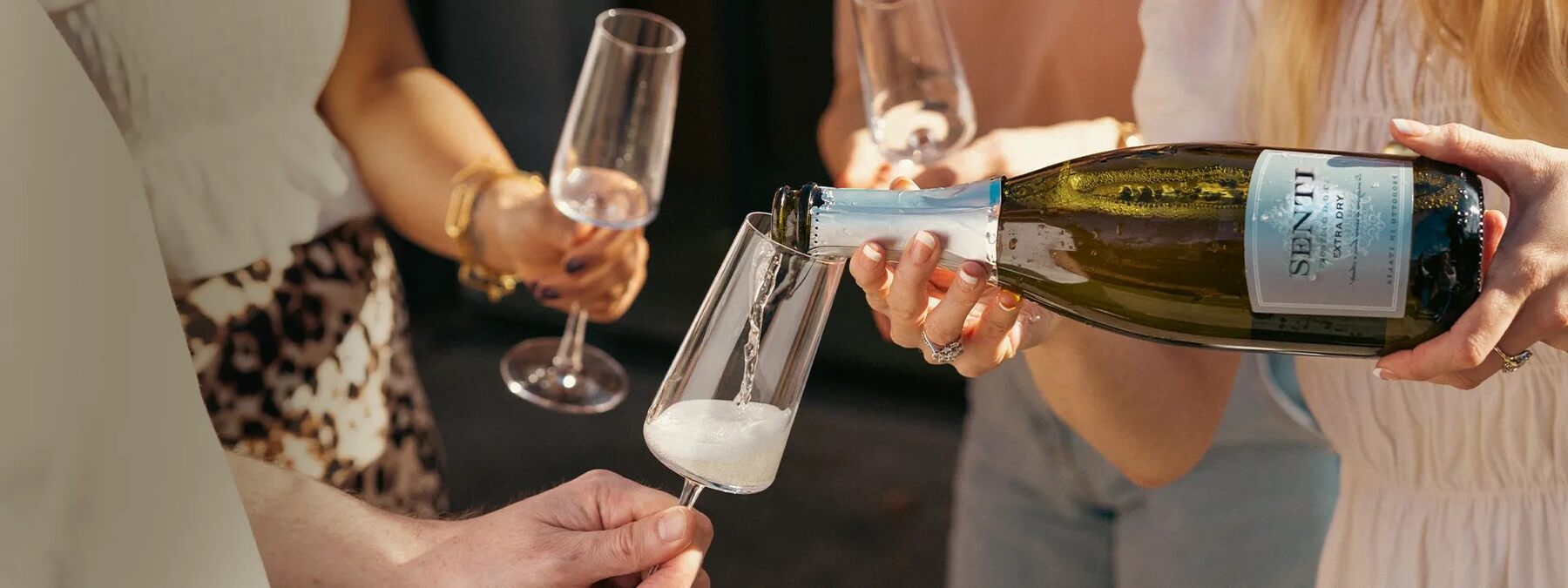 A glass of white wine being poured from a Virgin Wines bottle