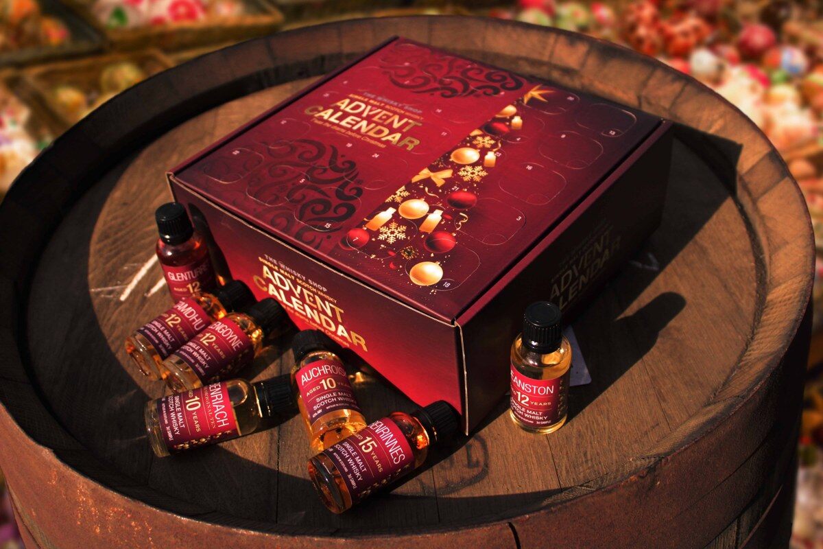 The Whisky Shop advent calendar, a red box, on top of a whisky barrel with miniature bottles around it